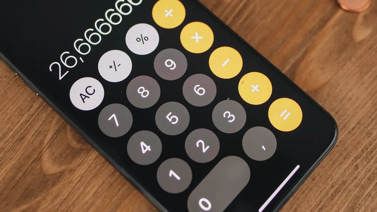 Calculatrice sur téléphone et pièces de monnaie